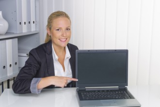 A young woman in her office with a laptop computer. Shows on the screen Austria