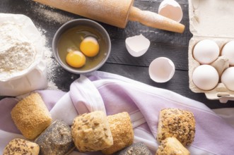 High angle view with a bag of flour, eggs, a rolling pin and freshly baked bread rolls, decorated