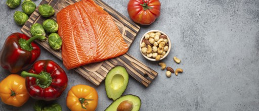 Fresh raw salmon fillet on wooden cutting board, organic bio vegetables and nuts on rustic stone