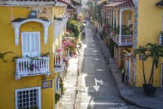 High angle view of a narrow street with historic houses with decorated balconies in sunshine,