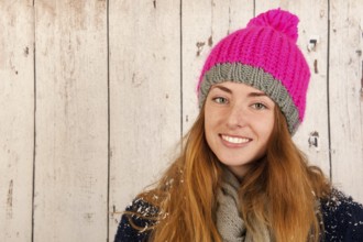 Portrait girl with pink winter hat in front of wooden background