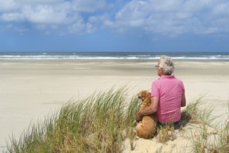 Man sitting with the dog at the beach