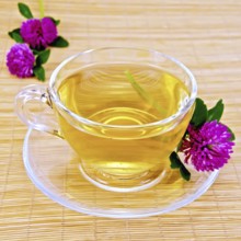 Herbal tea with flowers of clover in a glass cup on a bamboo napkin