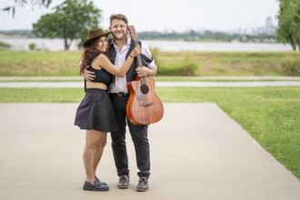 Couple of musicians pose looking at the camera in a park