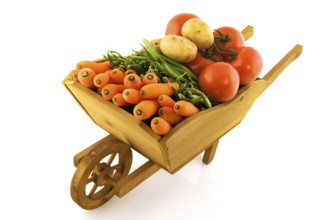 Wooden wheelbarrow full with fresh vegetables isolated over white
