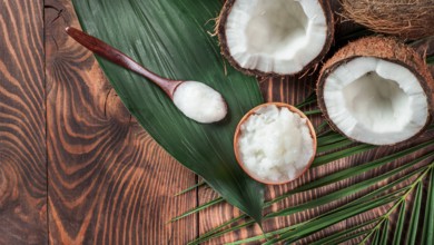 Top view of coconut MCT oil in bowl and in spoon and halved coco-nut on wooden table. Health