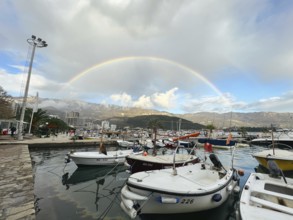 Yachts moored at the pier against the backdrop of a rainbow over the mountains.
