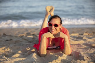 Happy middle-aged woman on the coast looks into the camera and smiles