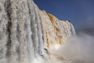 Close-up view of powerful Iguazu Falls in different colors and with blue sky