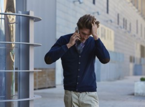 Young businessman talking smartphone phone walking on the street