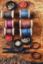 Six antiquated sewing threads and buttons on retro background