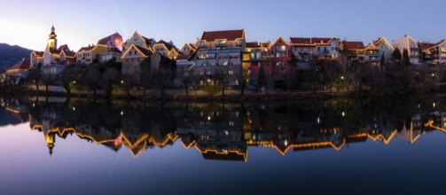 Christmas illuminated house facade of Frohnleiten reflected in the river Mur, panoramic shot, blue