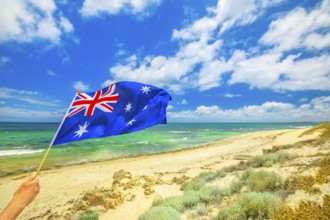 Australian flag waving on the foreground with coastal landscape of Mettams Pool, Trigg Beach, North
