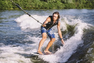Active wakesurfer jumping on wake board down the river waves. Surfer on wave. Male athlete training