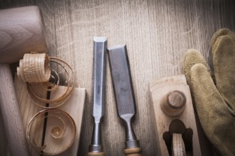Wooden bricks mallet curled up shavings planer firmer chisels leather gloves on wood background