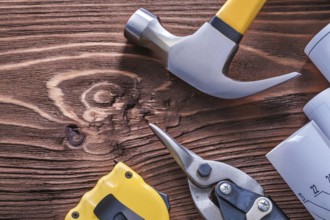 Claw hammer blueprints nippers and tape-measure on wood board construction concept