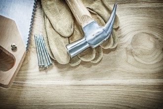 Set of claw hammer safety gloves handsaw nails on wooden board construction concept