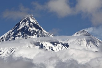 Stunning landscape view of snowy top of rocky volcanoes cones of Kamen Volcano and active