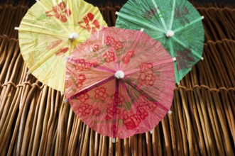 Colorful cocktail umbrellas on wooden base. Close up