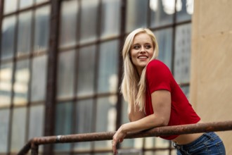 A beautiful blonde woman poses joyfully for the camera, showcasing her stylish spring clothing.