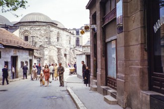 People walking along street of shops, next to domes of Brusa Bezistan museum, Sarajevo, Bosnia and