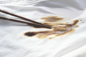 White shirt stained with soy sauce and chopsticks lying on it, no people, close-up, selective focus