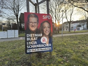 SPD election poster with two politicians, in the background a quiet city scene at sunset, election