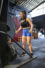 Vertical photo of a strong Chinese woman exercising with weights in a lat pulldown machine