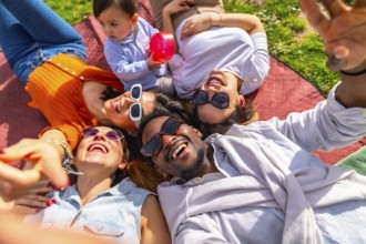 Group of cheerful multi ethnic friends taking a selfie while lying in a circle on a blanket at the