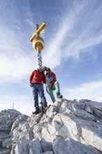 Couple, two mountaineers in front of a golden summit cross, summit of the Zugspitze, Wetterstein