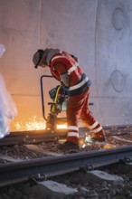 A worker grinding rails in a tunnel, sparks spraying, rail welding, track construction Hermann