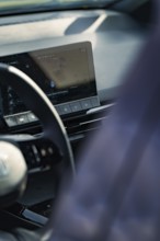 Detailed view of a modern car interior with steering wheel and display on the dashboard, e-car