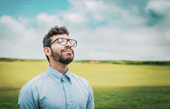 Relaxed young man breathing fresh air in the field. Serene man breathing fresh air in the field
