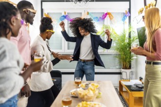 Multi-ethnic friends having fun in a home party dancing and drinking