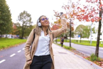 Latin woman wearing casual business clothes dancing while listening to music in the city