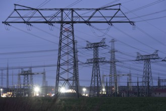 High-voltage pylons illuminated at dusk, industrial environment, quiet atmosphere, Wolmirstedt,