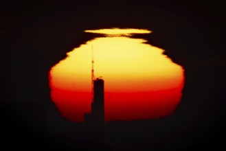 The top of the Commerzbank Tower in Frankfurt am Main stands out against the rising sun, Frankfurt