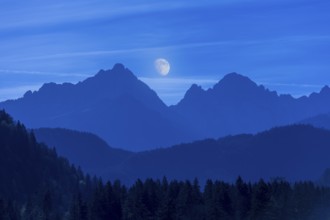 Beautiful mountain landscape at night with shining moon in the background, Schwangau, Ostallgäu,