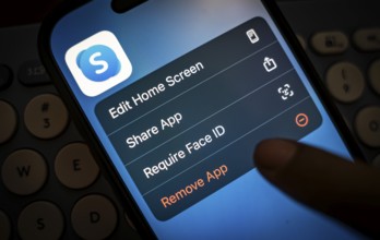 In this photo illustration, a person holds a mobile phone displaying Skype application, in