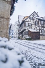 Snow-covered village street with traditional half-timbered houses in a quiet winter atmosphere,