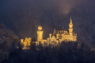 An enchantingly illuminated castle towers over a snow-covered mountain forest, Neuschwanstein,