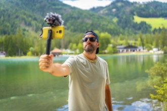 Content creator filming a video with a smartphone and external microphone at lake dobbiaco in the