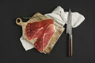 Overhead view of jamon iberico cured pork meat on a wooden cutting board, accompanied by a sharp