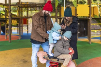 Parents watching their children joyfully riding a spring rider on a colorful playground, creating