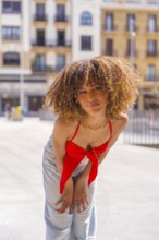Vertical photo of a cute beauty woman with curly hair looking at camera in the city