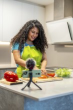 Vertical photo of a latin young female influencer recording a health food tutorial at home