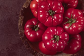 Pink tomatoes, in a rustic wooden bowl, close-up, no people