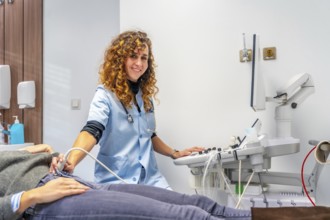 Female doctor smiling at camera while performing an ultrasound to a pregnant woman into the