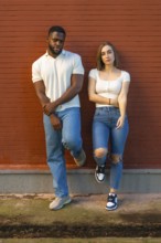 Vertical portrait of multiracial friends standing and looking at camera on a urban wall outdoors