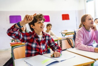Elementary school student raising hand to answer a question during class, showing eagerness to